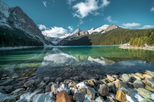 breathtaking-shot-of-beautiful-stones-under-turquoise-water-of-a-lake-and-hills-in-the-background